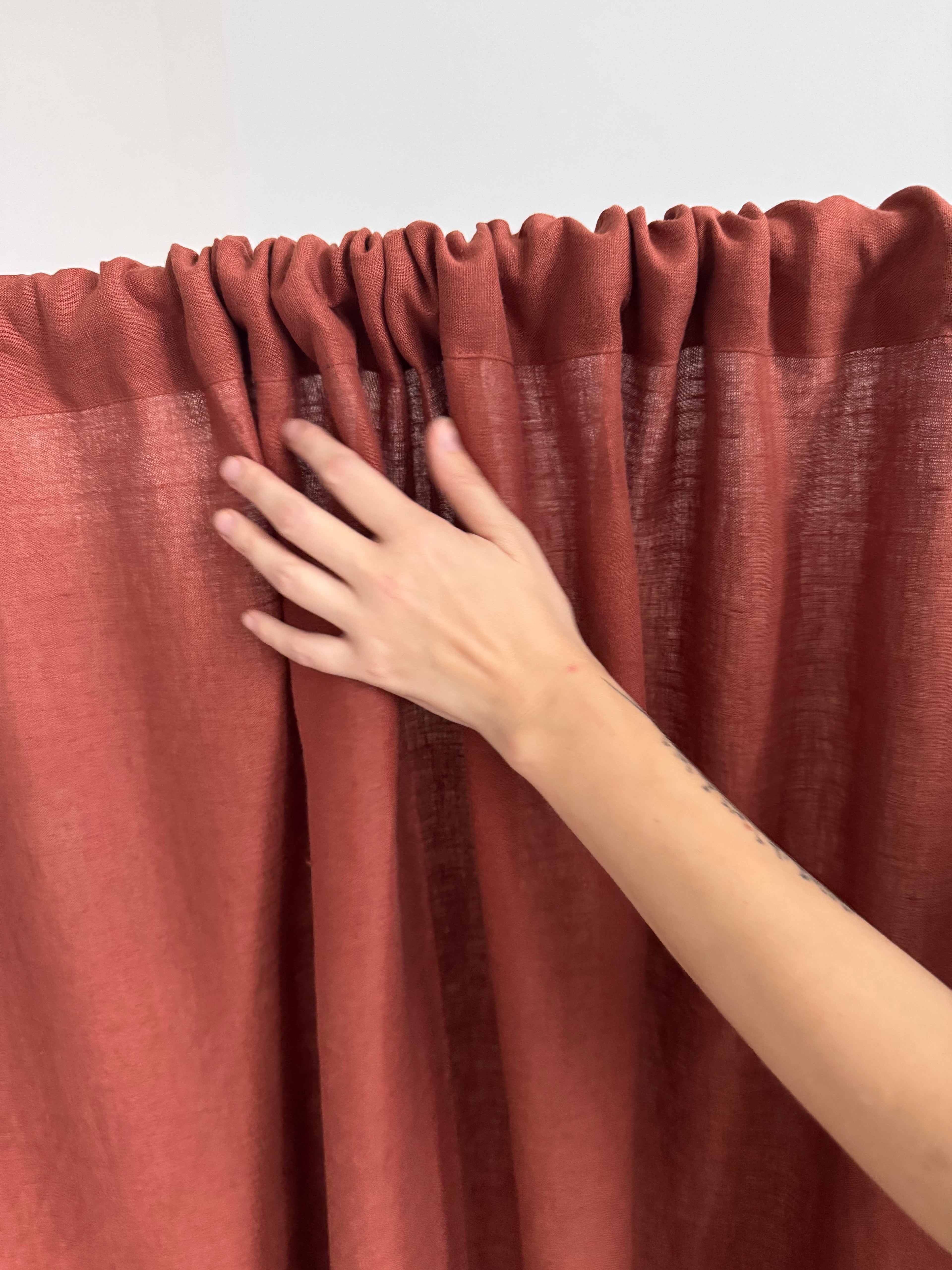 Hand touching a red curtain against a white background


