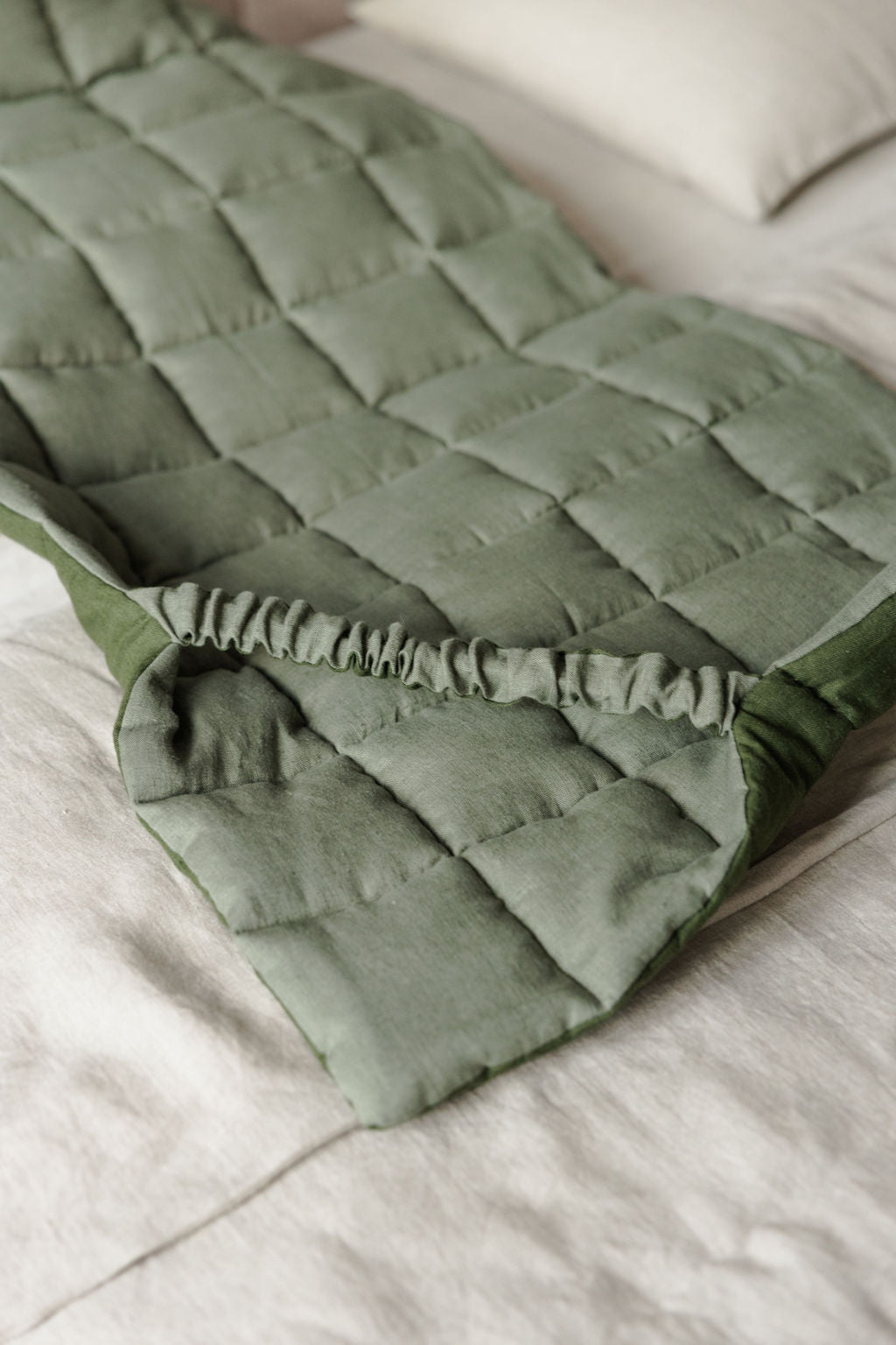 Green quilted blanket on a bed