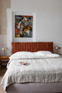 Bedroom with a red quilted headboard and abstract art on the wall.