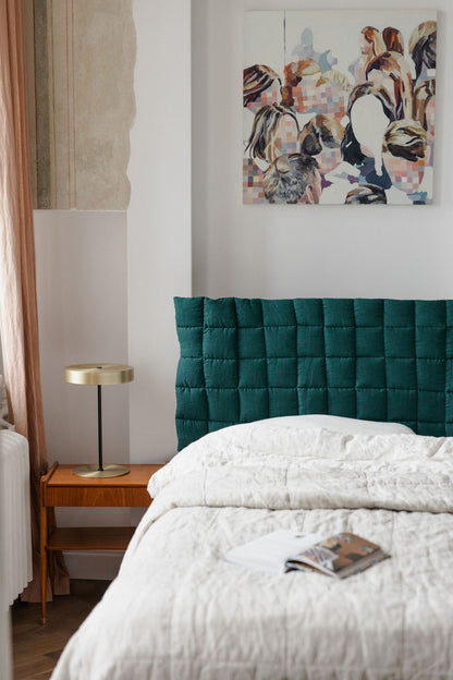 Bedroom with teal headboard and abstract painting on wall