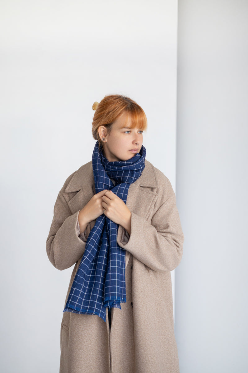 Person wearing blue linen scarf against a plain background