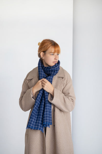 Person wearing blue linen scarf against a plain background