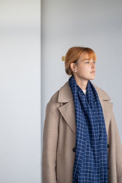 Person wearing blue linen scarf against a plain background